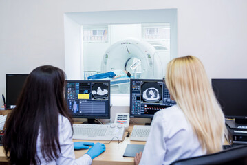 Radiologist and assistant in the control room of computed tomography at hospital