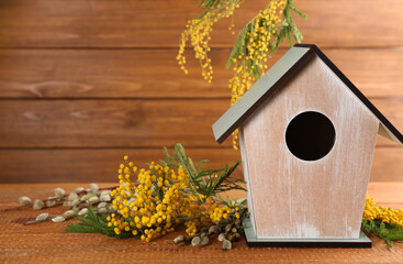 Fototapeta na wymiar Stylish bird house and fresh flowers on wooden table. Space for text