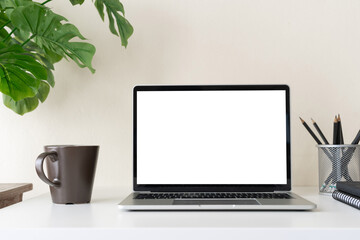 Fototapeta premium Laptop computer with blank screen for mockup on modern contemporary workspace desk with coffee cup and office supplies. Home office workplace.