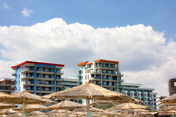 Low angle view of houses and beach umbrellas on a beach, with cloudy sky in the background