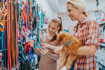 Mother and daughter with their poodle puppy in pet shop.