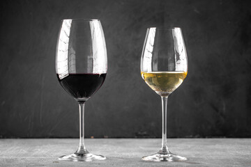 Side view on two glasses of red and white wine on the grey background
