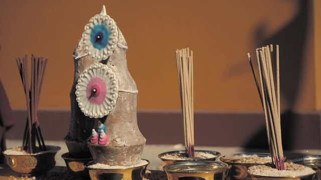 Slow motion pan of ritual buddhist objects (tormas, incense and water bowls).