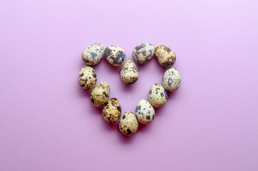 Quail eggs in the shape of a heart. Quail eggs on violet background.