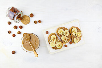 Homemade raw organic hazelnut paste. Toasts with hazelnut butter and banana.    Hazelnuts in jar on...