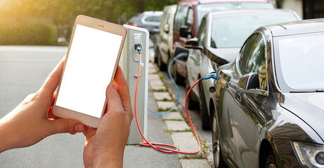 Hands with smartphone on a background of a car at the charging station for electric vehicles.  White screen, you can add your content here	