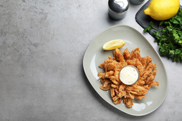 Fried blooming onion with dipping sauce served on grey table, flat lay. Space for text