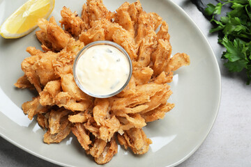 Fried blooming onion with dipping sauce served on grey table, flat lay