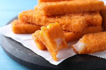 Fresh breaded fish fingers served on light blue wooden table, closeup