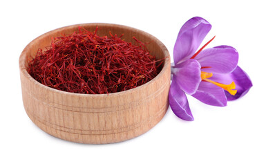 Dried saffron in wooden bowl and crocus flower on white background