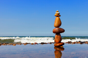 Rock zen pyramid of colorful pebbles standing in the water on the background of the sea