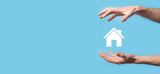 Male hand holding house icon on blue background. Property insurance and security concept.Real estate concept.