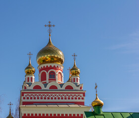 Fototapeta na wymiar The golden domes of the Orthodox church with crosses on the background of a clear blue sky.