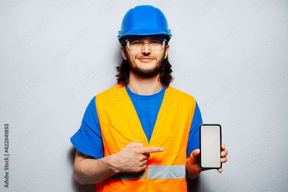 Wall mural studio portrait of young construction worker engineer wearing safety equipment, pointing finger at s