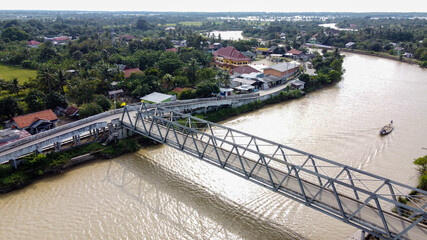Aerial drone view of A long bridge to the end of the river connects the two villages at Bekasi with noise cloud. 