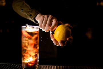 close-up of male hands with lemon that carefully peels off zest from it with knife