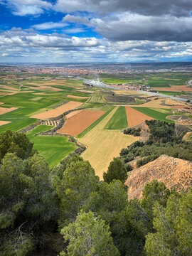 aerial image of the Corredor del Henares with the town of Taracena and cereal fields in the foreground, the city of Guadalajara and in the background the skyline of Madrid on a cloudy day, vertical