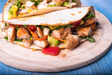 Mexican tacos with grilled chicken and vegetables on a wooden board close-up
