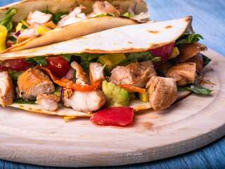 Mexican tacos with grilled chicken and vegetables on a wooden board close-up