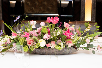 Fototapeta na wymiar beautiful arrangement of pink flowers with greenery, on a table with a white tablecloth, indoors, hotel, in the afternoon. Florist work, wedding decor, holidays. Profitable business, table decoration