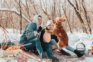 Couple in love playing with dog on winter picnic