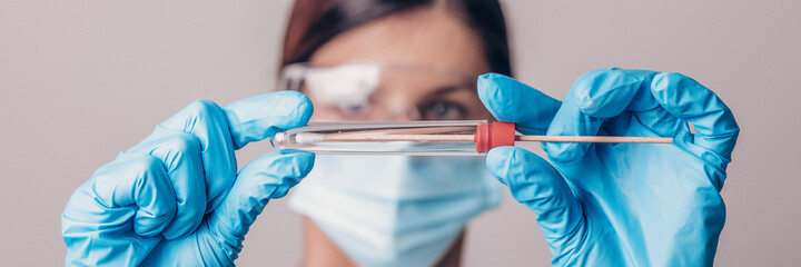 Medical staff holding test kit for PCR testing virus covid19. Coronavirus COVID-19 swab test kit, PPE protective mask and gloves, tube for taking OP NP patient specimen sample, DNA RNA