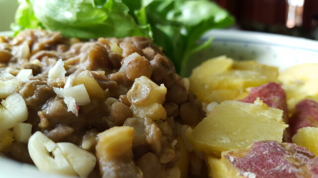 Lentil peas garnished with garlic and sweet potation. A bit of water-cress is blurred in the background. 