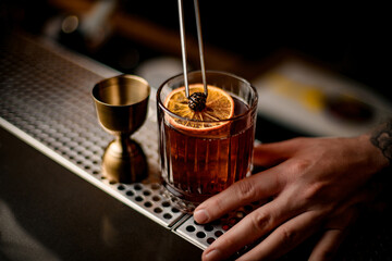 beautiful view on glass with cocktail decorated with orange slice and small pine cone