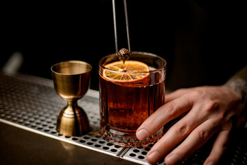 view on glass with cocktail decorated with orange slice and small pine cone