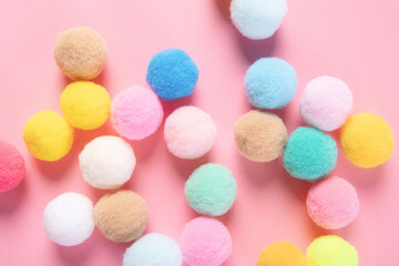 Closeup shot of colorful soft pom pom balls on pink background - obrazy, fototapety, plakaty