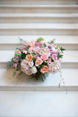 Fototapeta na wymiar a large bouquet of pink, white flowers, on a light staircase. Bouquet, composition for a holiday, celebration. Flower trade, private business, floristic decoration