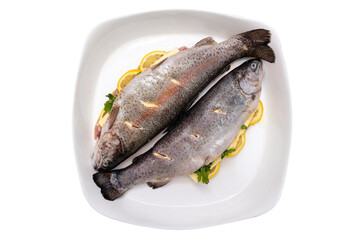 Fresh, raw two trout lying on a plate, stuffed with butter, parsley and lemon slices, isolated on a white background with a clipping path, top view.