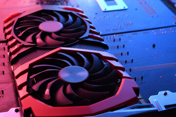 Computer game graphics card, videocard with two coolers on circuit board ,motherboard background. Close-up. With red-blue lighting