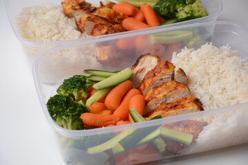 Healthy balanced lunch boxes. Grilled chicken, carrots, cucumbers, broccoli, and white rice. Lunch boxes with food ready to go for work or school. Office food lunch concept