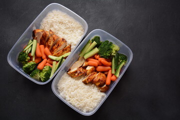 Healthy balanced lunch boxes. Grilled chicken, carrots, cucumbers, broccoli, and white rice. Lunch boxes with food ready to go for work or school. Office food lunch concept