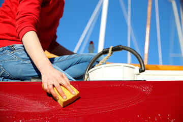 A young woman cleaning a classic sailing yacht - 422057603