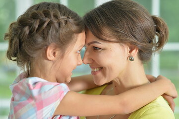 Close-up portrait of a charming little girl hugging with mom at home