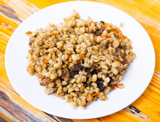 pearl barley porridge with mushrooms on a white plate