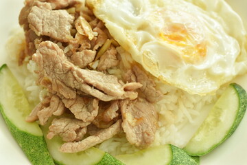 fried slice pork meat with garlic and pepper topping egg on plain rice in plate