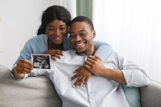 Happy black couple looking at baby sonogram