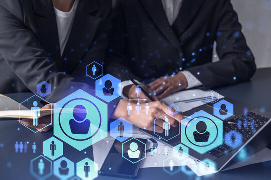 Two HR specialists analyzing the market of freshers to boost the intern program at international consulting company. Hiring new talented crew. Social media hologram icons. Women in business.