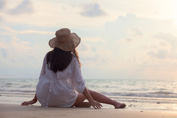 young woman in straw hat enjoying evening by the beach