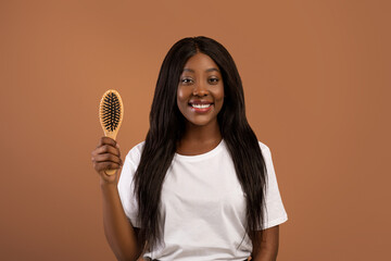 Attractive black woman holding wooden hair brush