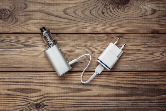 Vaping device with charger on wooden background
