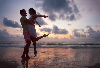 Fototapeta premium The image of silhouette of two people in love at sunset in Thailand