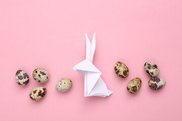 Easter composition. Origami Easter bunny and quail eggs on a pink pastel background. Top view