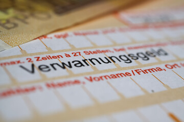 Viersen, Germany - March 1. 2021:  Makro closeup of german bank transfer form with speeding ticket (verwarnungsgeld) with euro money cash note