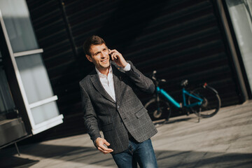 Young businessman walking away from the ebike and using mobile phone