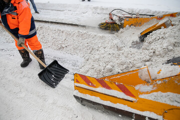 Snow plow and snow truck cleaning the streets during a snow storm in night maintenance action in...