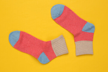 Warm colored socks on a yellow background. Top view